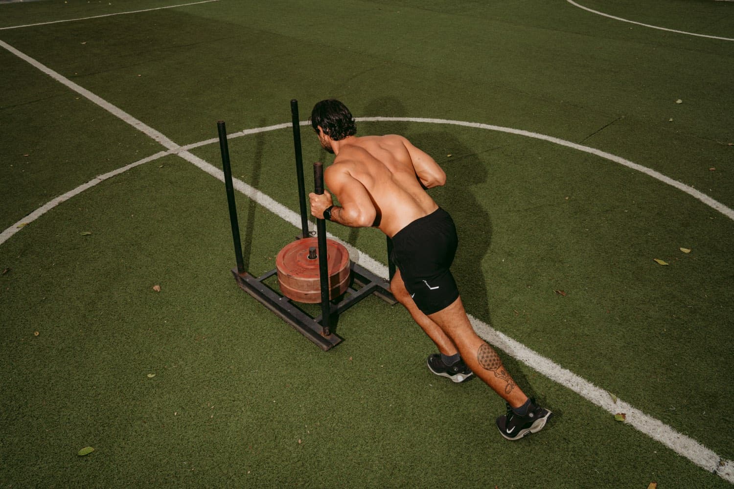 A guest pushing a weighted sled across the training pitch at Pronoia Bali
